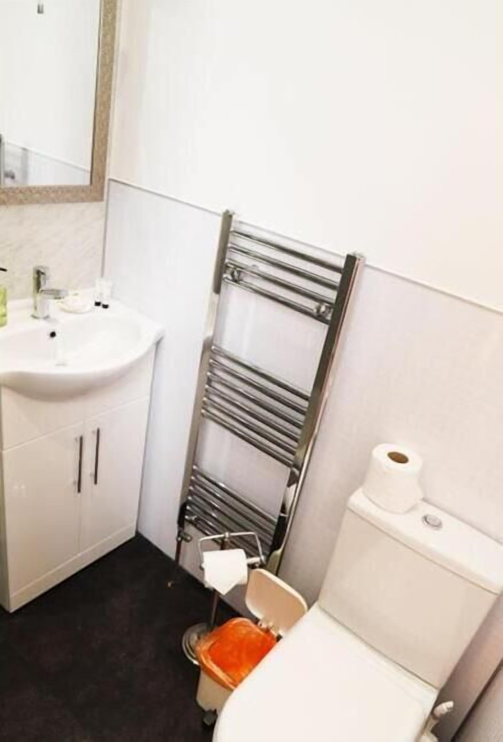 Une petite salle de bain avec un lavabo blanc, un miroir, un porte-serviettes et des toilettes.