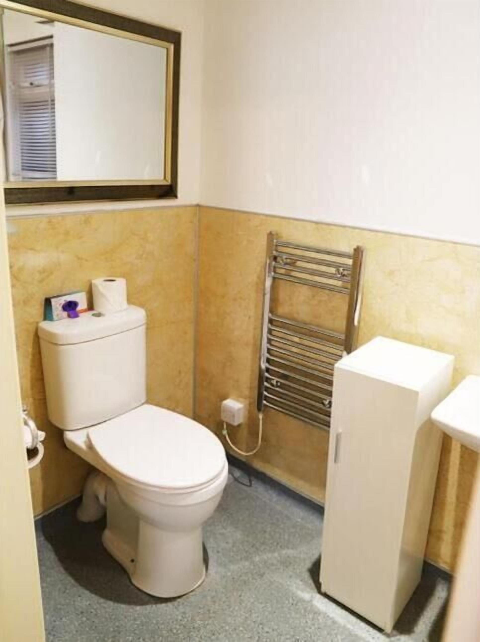 A small bathroom with a toilet, a sink, and a towel rack.