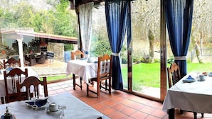 A patio dining area with tables and chairs, a view of the garden, and a covered seating area.