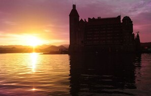 A castle-like building with a prominent tower, situated on a body of water with a sunset in the background. - Hotel Kawakyu (Shirahama)