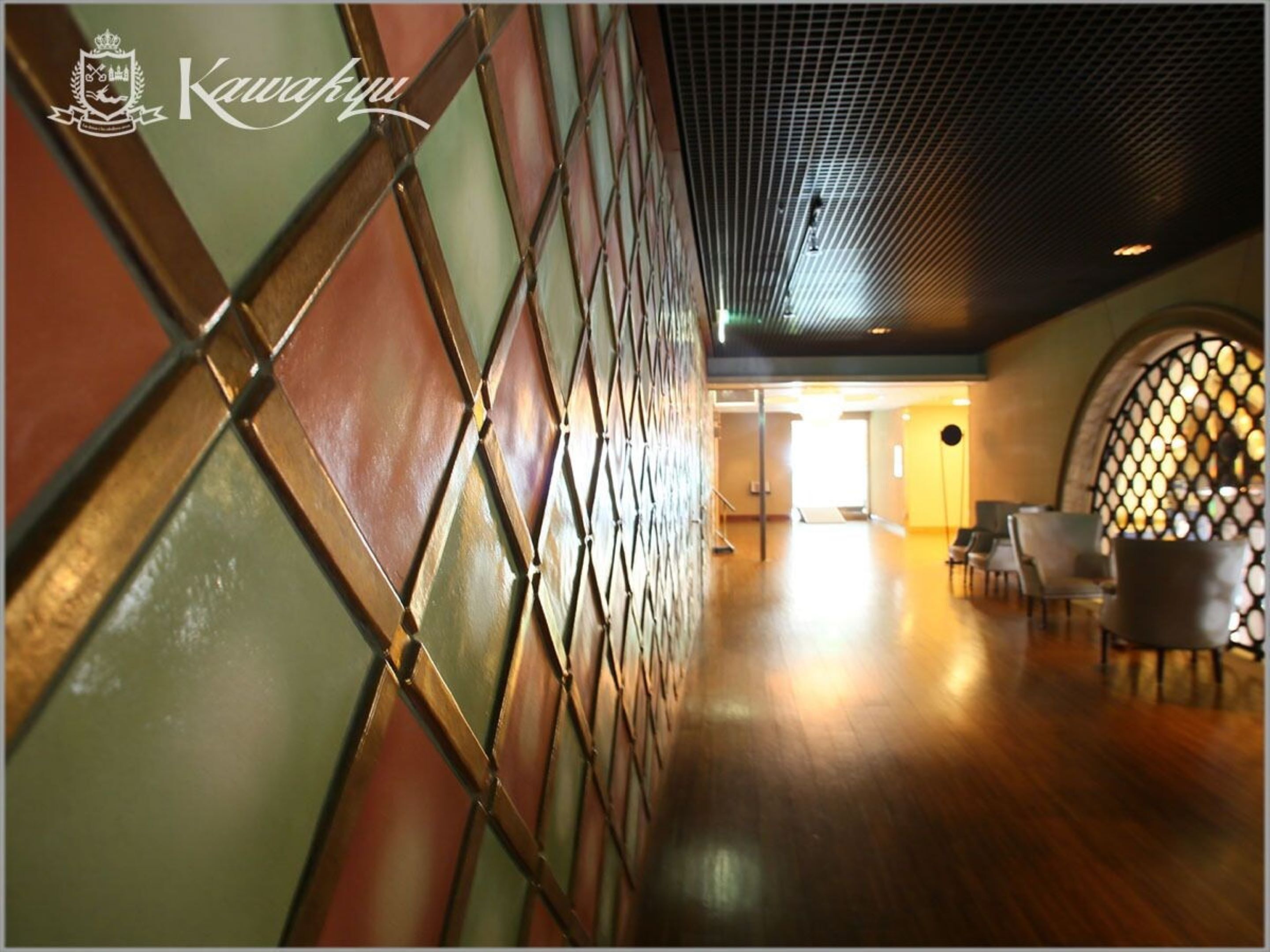 A corridor with a patterned wall and a seating area with chairs.