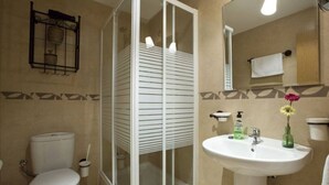 Ein Badezimmer mit Toilette, Duschkabine, Waschbecken und Spiegel.