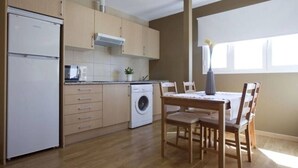 Eine kleine Küche mit integriertem Waschmaschine, Holzausstattung und einem Essbereich mit Tisch und Stühlen.