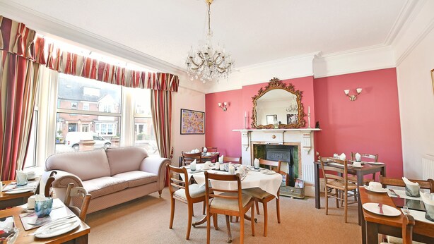 A dining area with a fireplace, a sofa, and a chandelier. - Virginia Lodge (Stratford-upon-Avon)