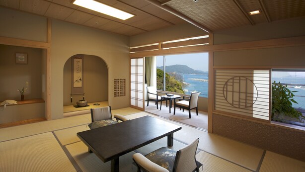 A traditional Japanese room with tatami flooring, a low table, and a view of the sea. - Kochoran (Toba)