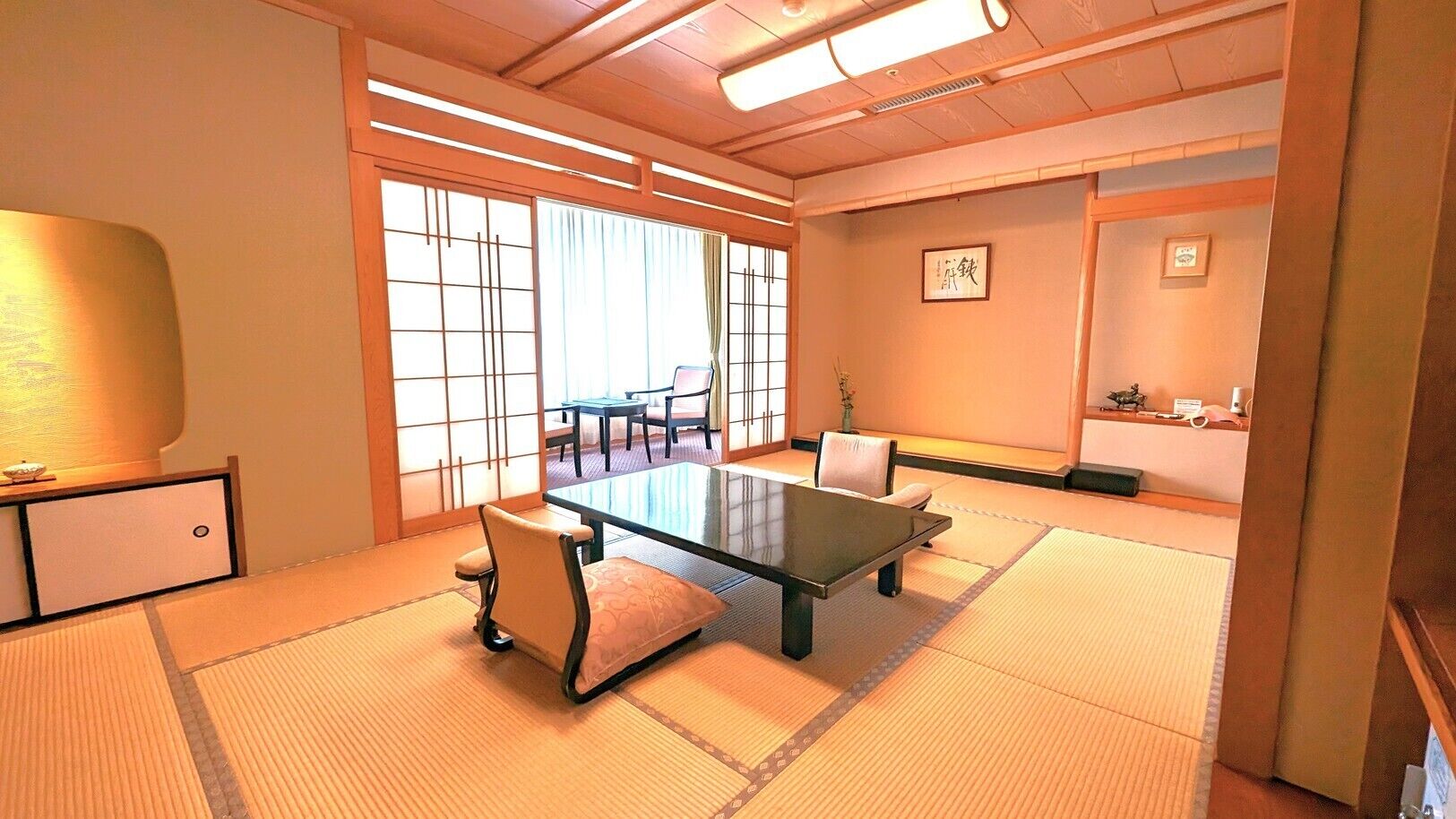 A traditional Japanese room with tatami flooring, a low table, and chairs.