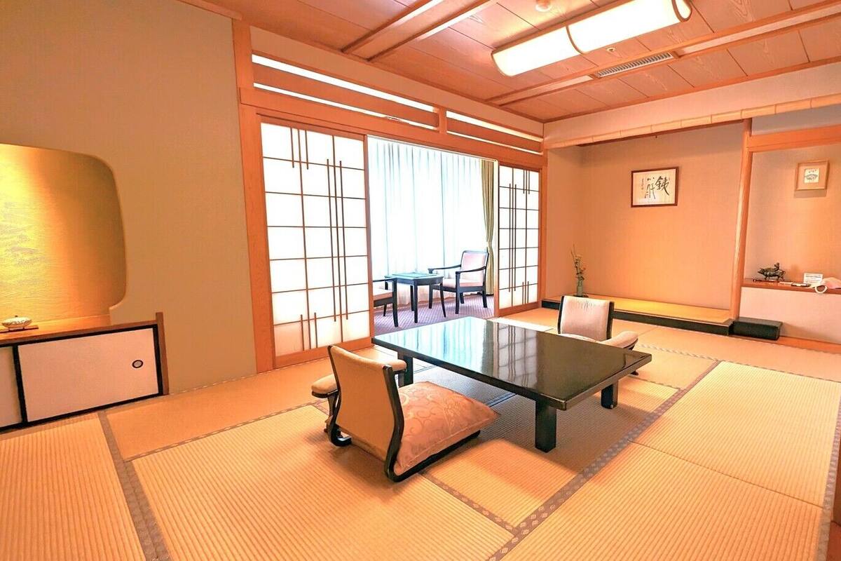 A traditional Japanese room with tatami flooring, a low table, and chairs.