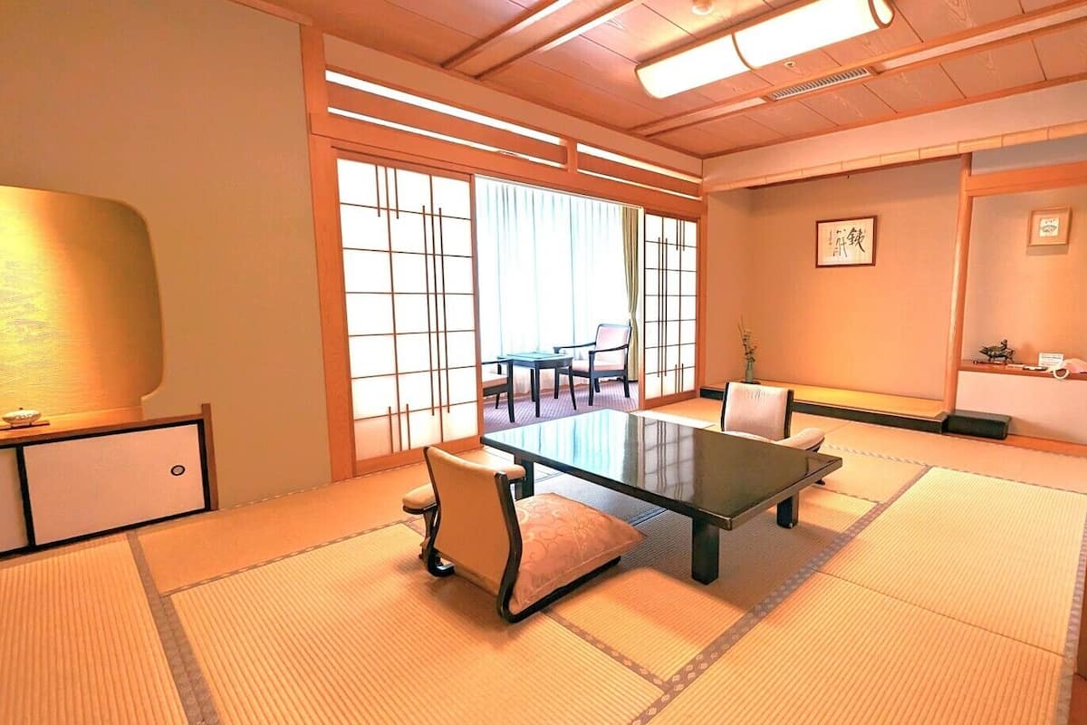 Una habitación japonesa tradicional con suelo de tatami, una mesa baja y sillas.