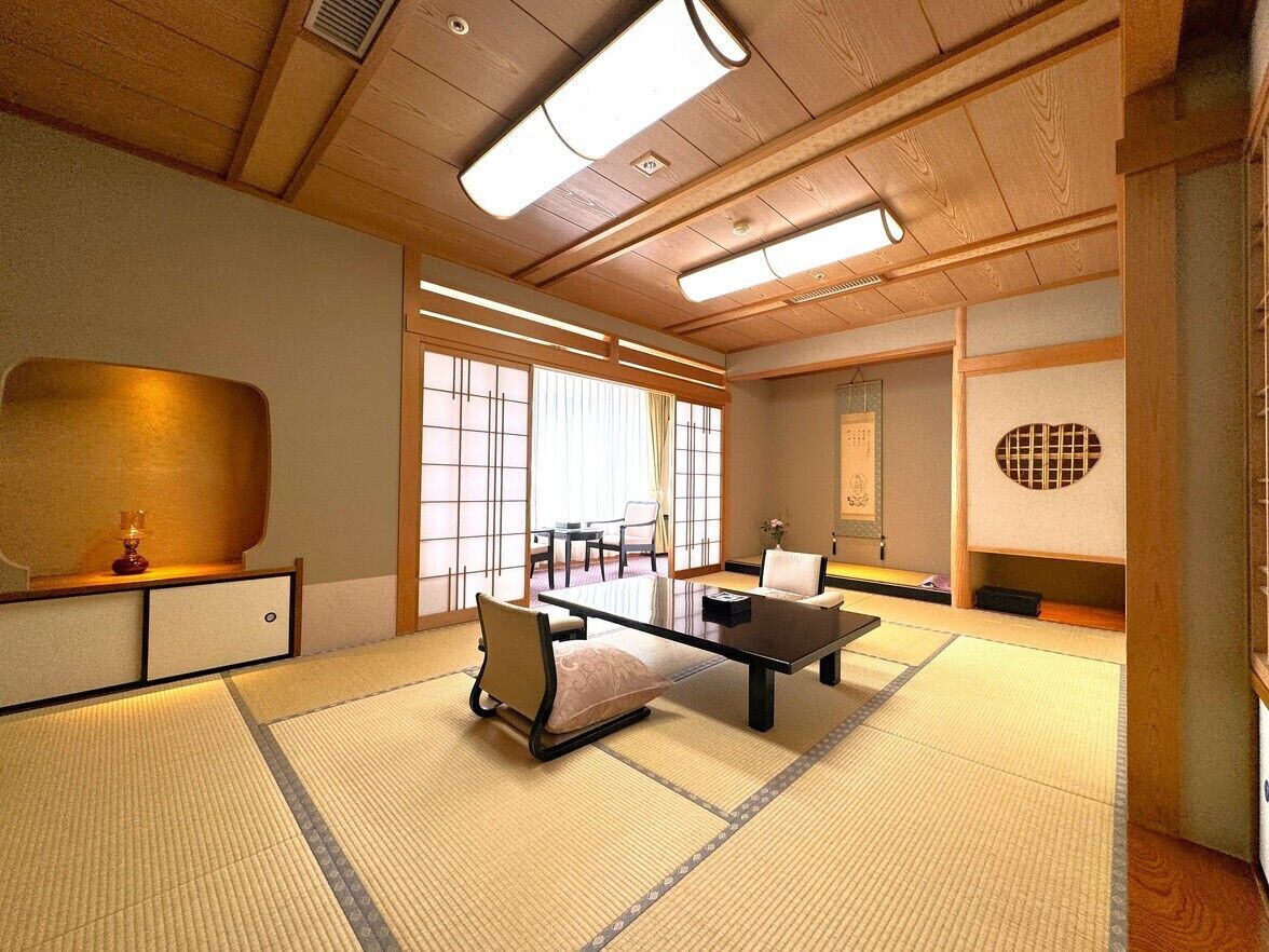 A traditional Japanese room with tatami flooring, a low table, chairs, and sliding doors.