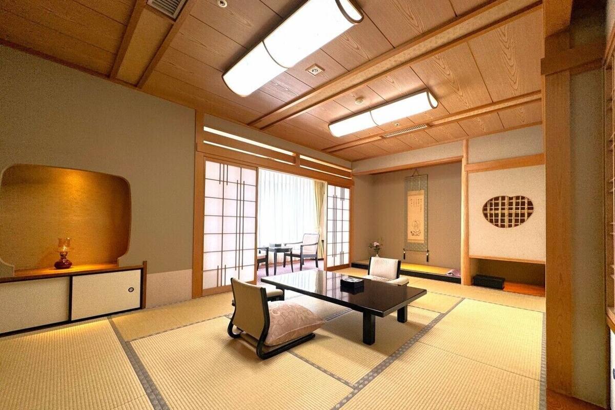 A traditional Japanese room with tatami flooring, a low table, chairs, and sliding doors.