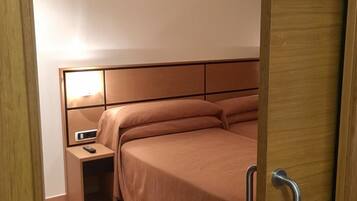 Un dormitorio con cama, mesita de noche y velador.