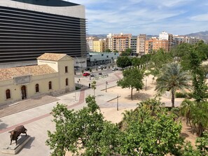 A plaza with a bull statue, a modern building, and a street with cars and pedestrians. - Hotel Doña Lola (Castelló de la Plana)
