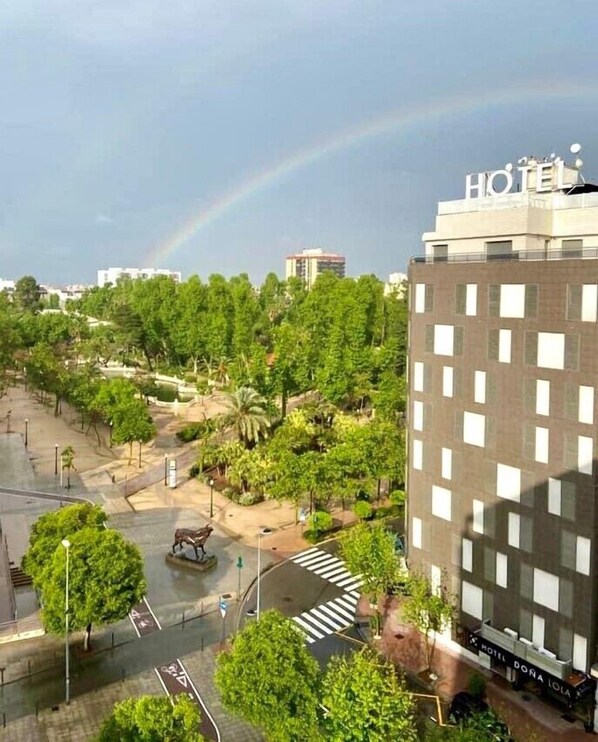 A hotel with a modern design, featuring a rooftop garden and a view of a cityscape with a rainbow in the background. - Hotel Doña Lola (Castelló de la Plana)