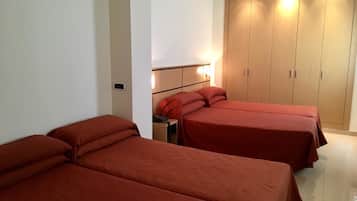 A hotel room with two single beds, a wardrobe, and a bedside table with a lamp.