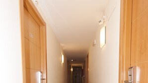A corridor with wooden doors and light fixtures on the walls. - Hostal Goyma III (San Fernando de Henares)