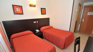 A hotel room with two single beds, a nightstand with a phone, and a desk with a chair. - Hostal Goyma III (San Fernando de Henares)