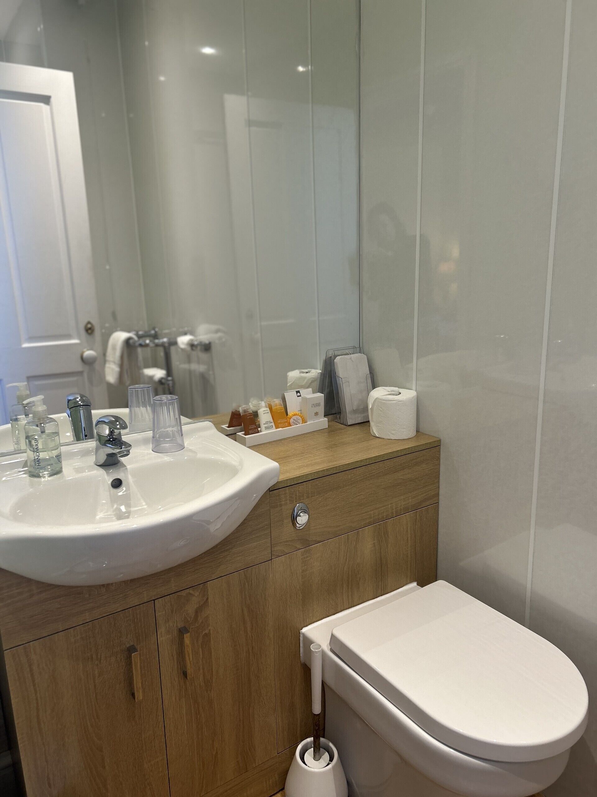 Un baño moderno con un lavabo blanco, tocador de madera y un inodoro.