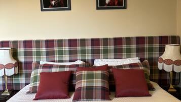 Una cama con colcha y almohadas a cuadros, flanqueada por dos cuadros en la pared.