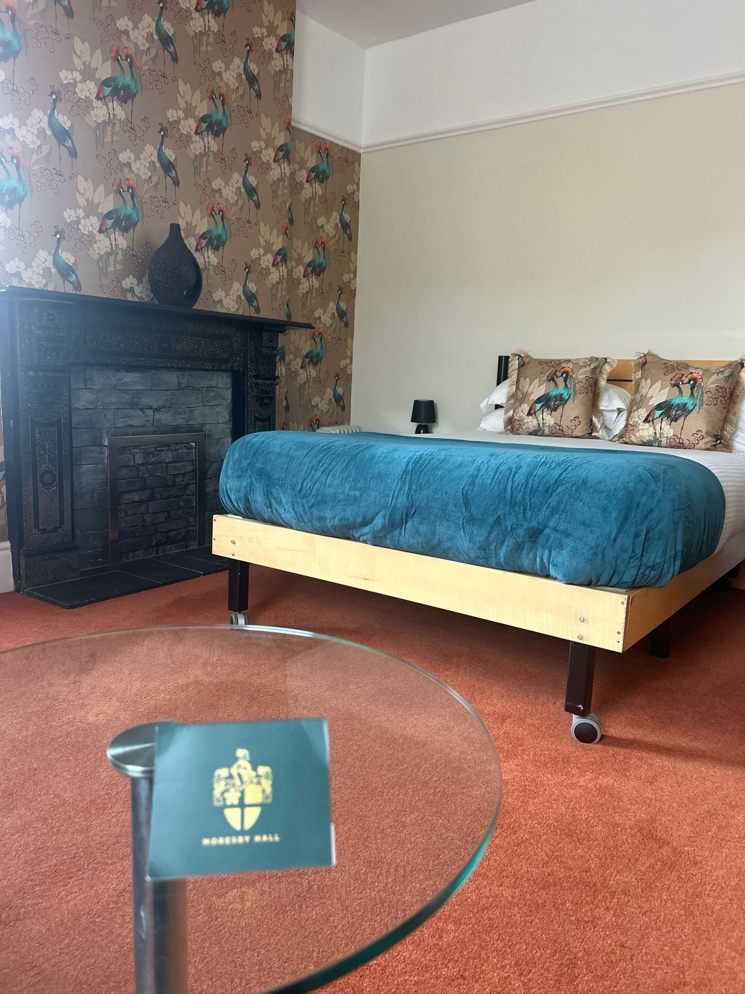 Un dormitorio con una cama, una chimenea y suelo cubierto de alfombra.