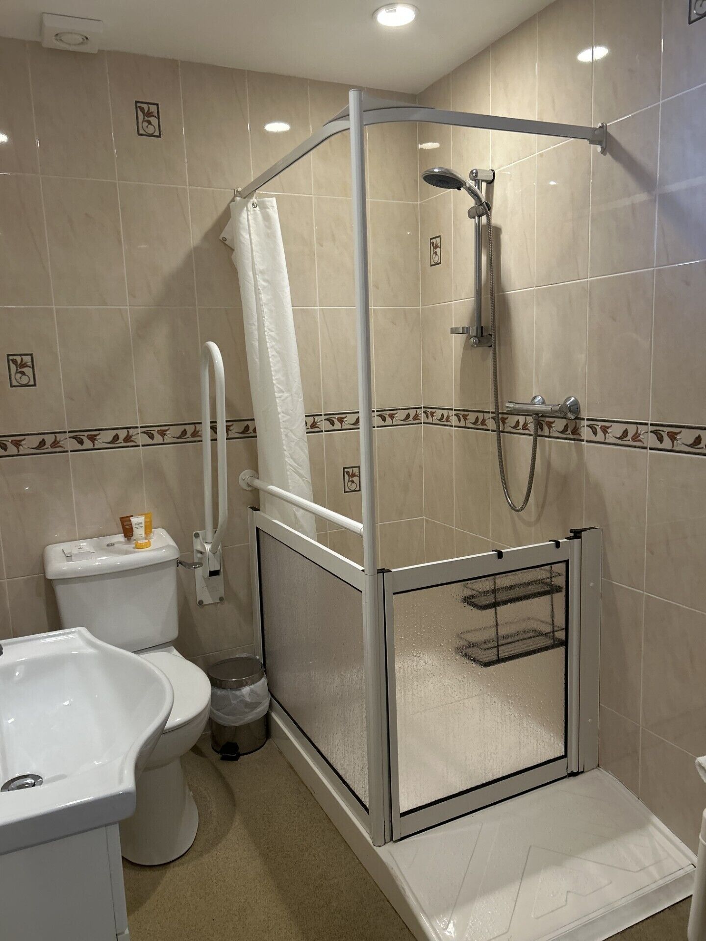 A modern bathroom with a glass-enclosed shower, a toilet, and a sink.