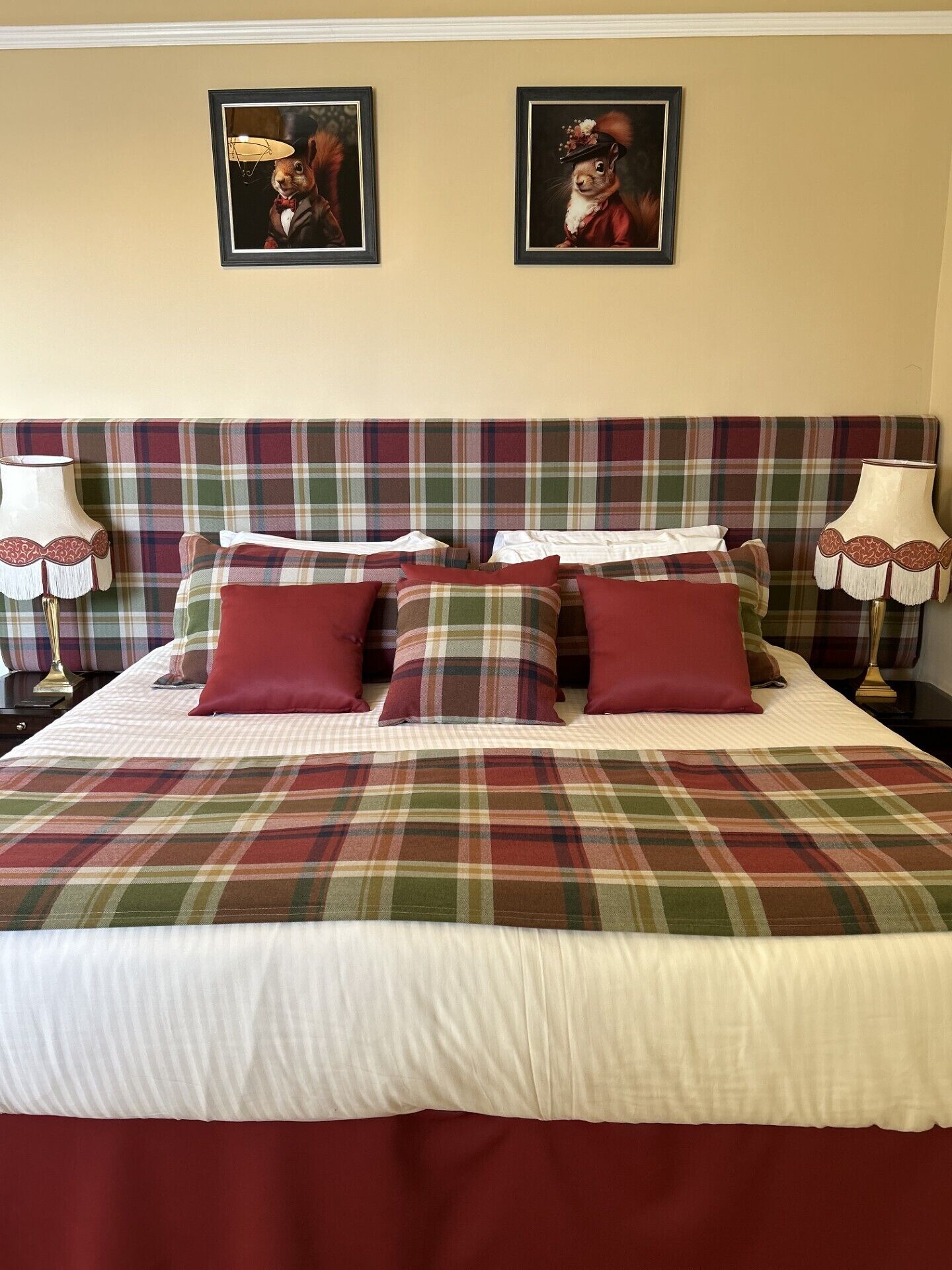 A bed with a plaid headboard, multiple pillows, and two wall-mounted lamps.