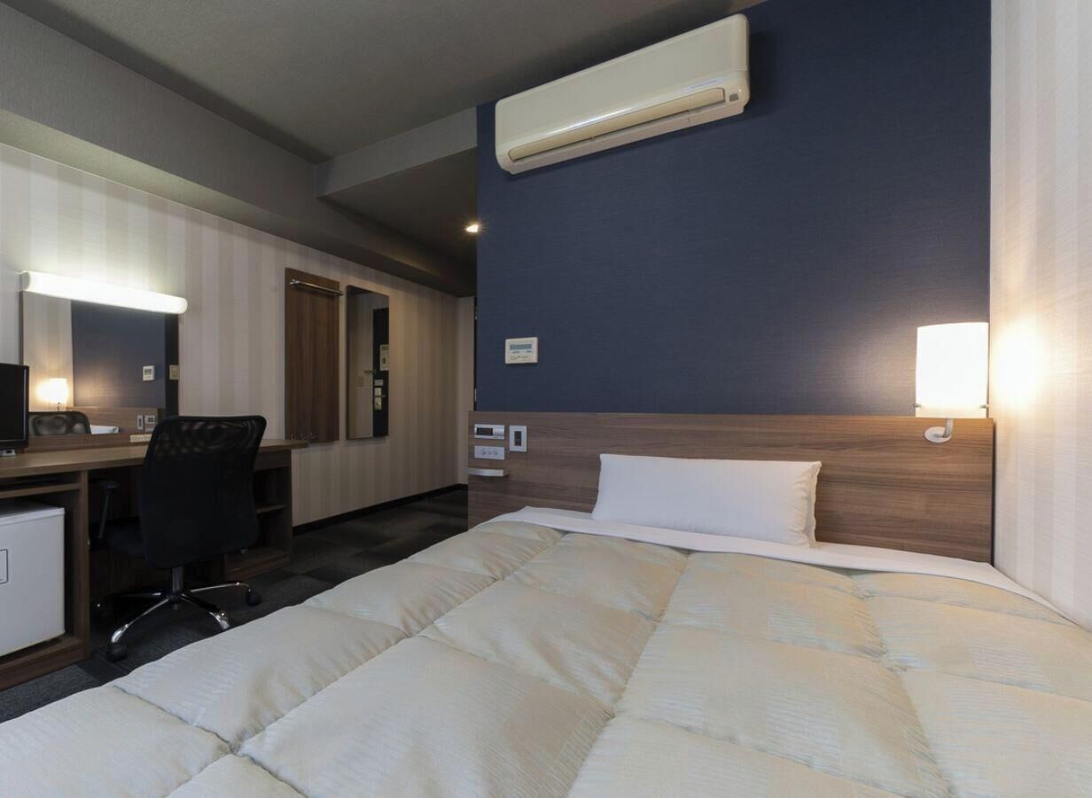 Une chambre d’hôtel équipée d’un lit, d’un bureau, d’une chaise et d’un appareil de climatisation.