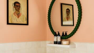 Ein Badezimmer mit Waschbecken, Spiegel, einem gerahmten Kunstwerk und einem grünen Dekowreath.