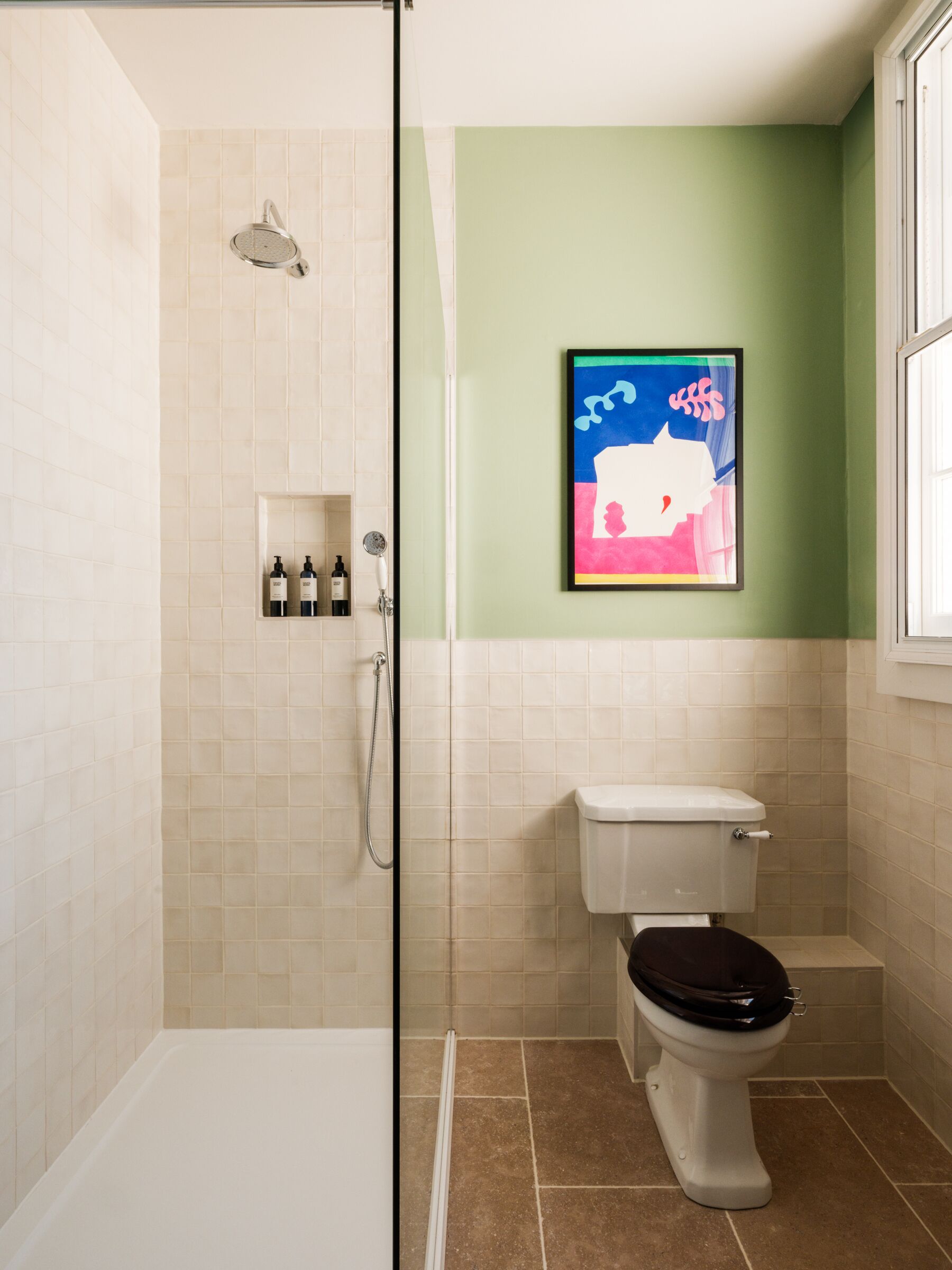 Een badkamer met een douche, toilet en een plank met toiletartikelen.