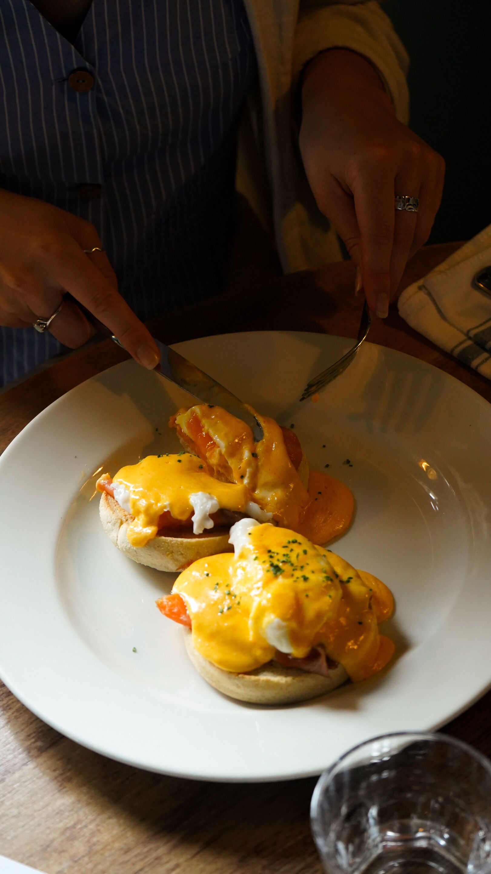 A person cutting a plate of eggs benedict.