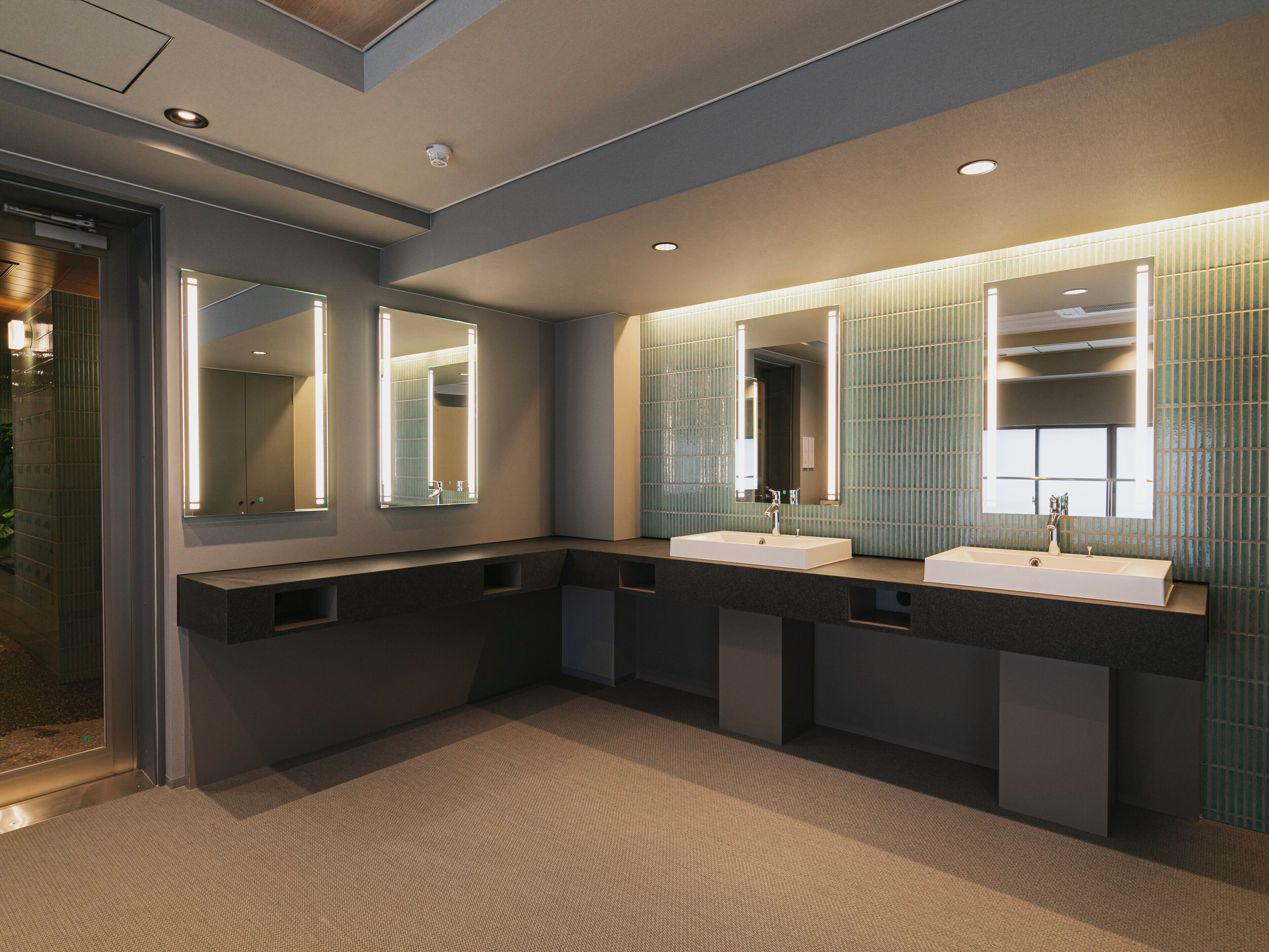 A modern bathroom with two sinks, large mirrors, and recessed lighting.