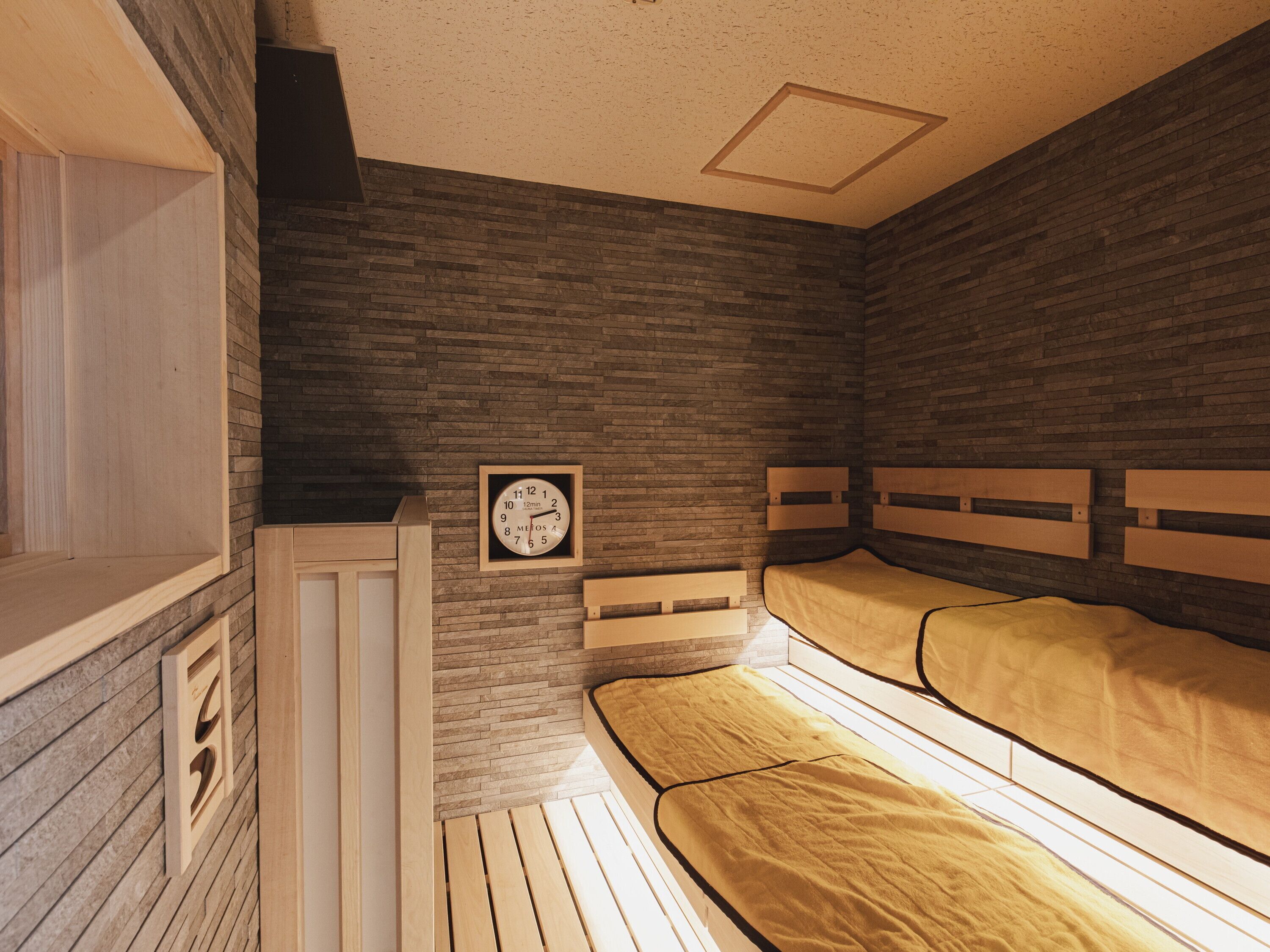 A room with a bed, a wooden headboard, a clock, and a window.