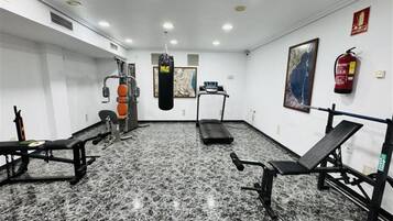 Un gimnasio con un saco de boxeo, cintas de correr y máquinas de pesas.