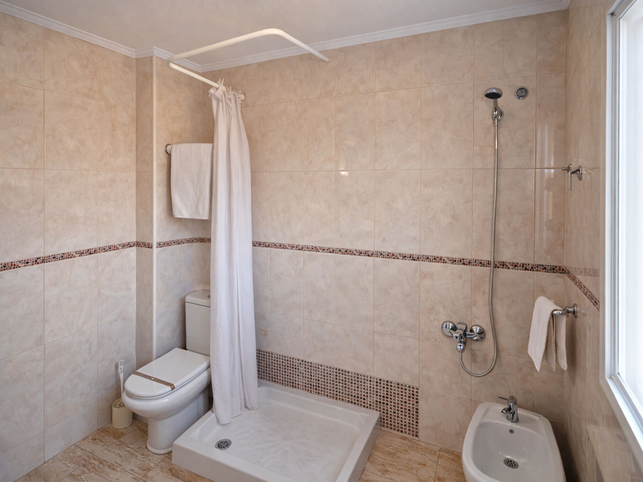 A bathroom with a shower, toilet, bathtub, and bidet.