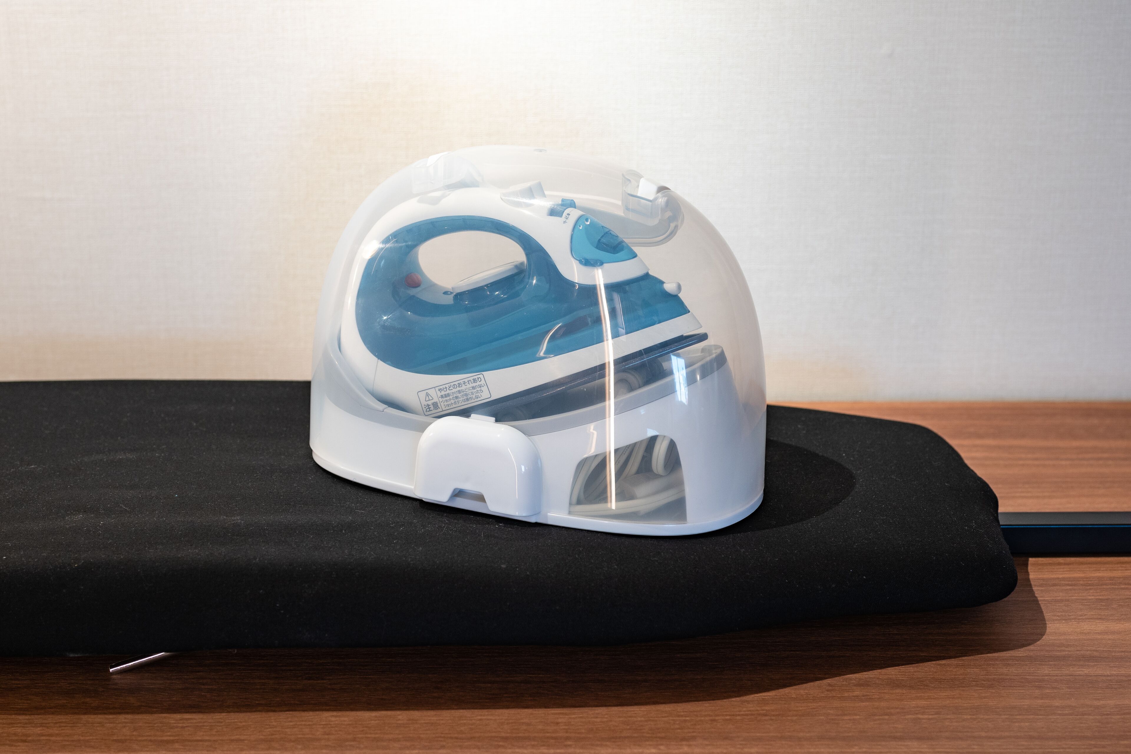 Un ferro da stiro bianco e blu su un tappetino nero.