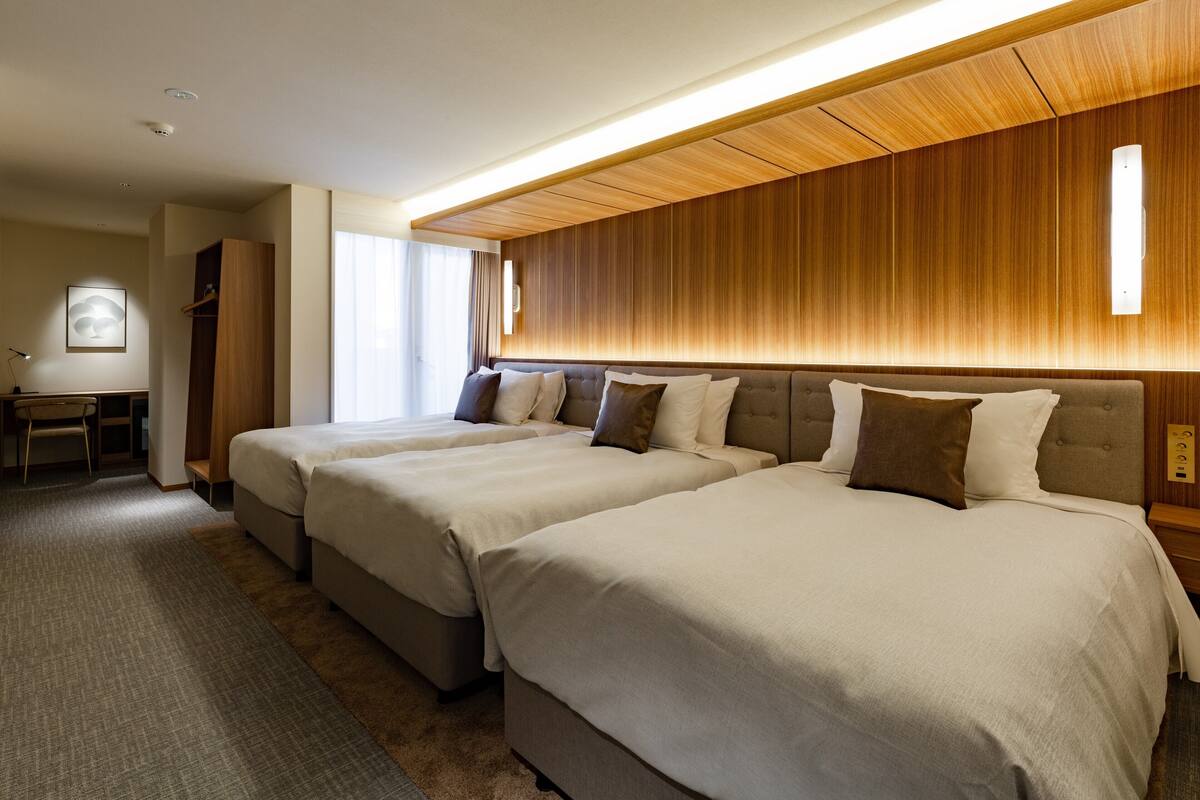 Una habitación de hotel con dos camas, un escritorio y un armario.