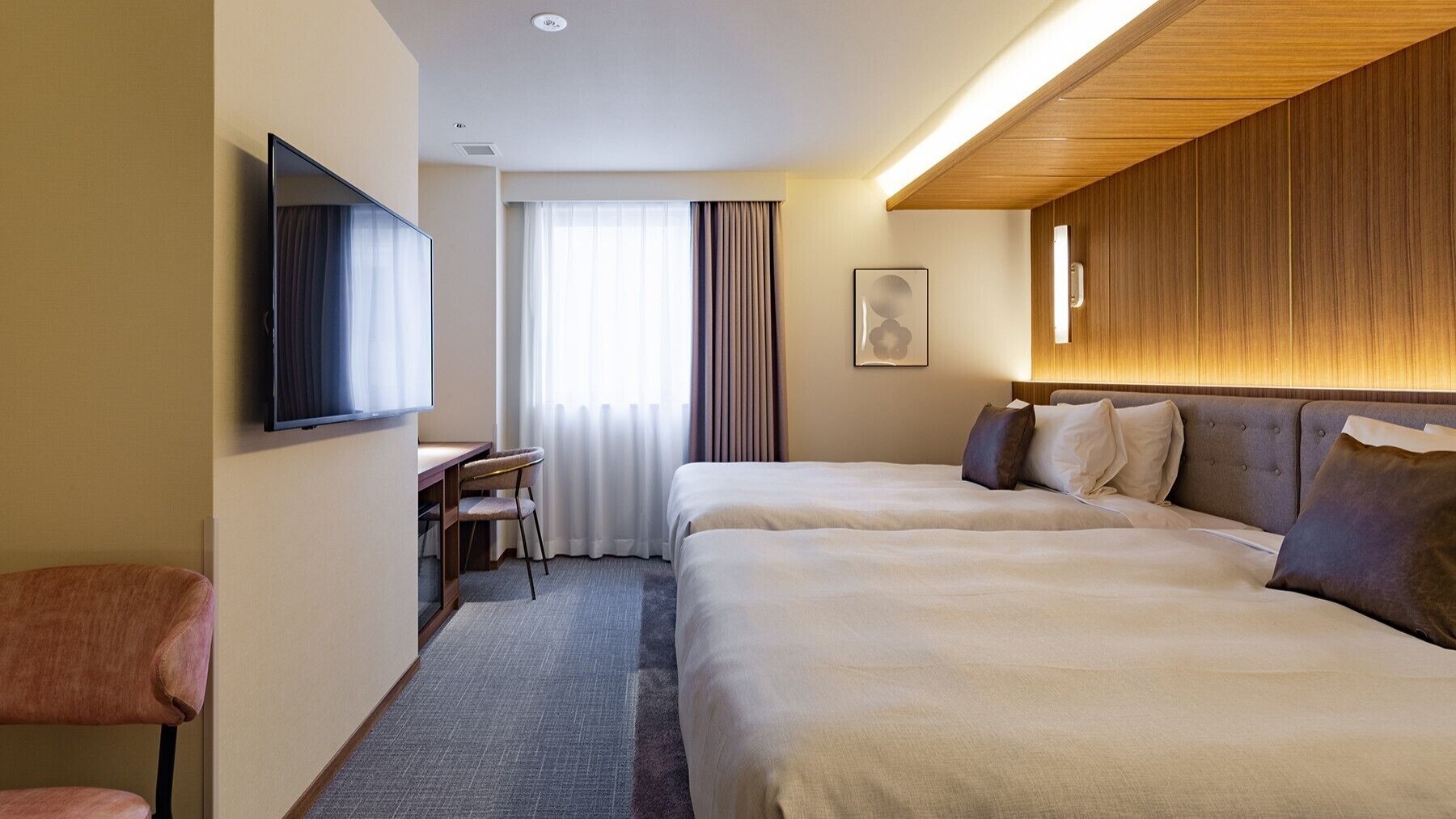 A hotel room with two beds, a desk, a chair, a TV, and a window with curtains.