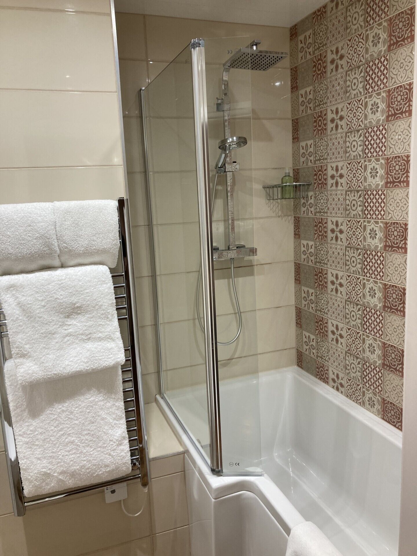 Une douche avec une paroi en verre, une baignoire blanche et un porte-serviettes avec des serviettes blanches.