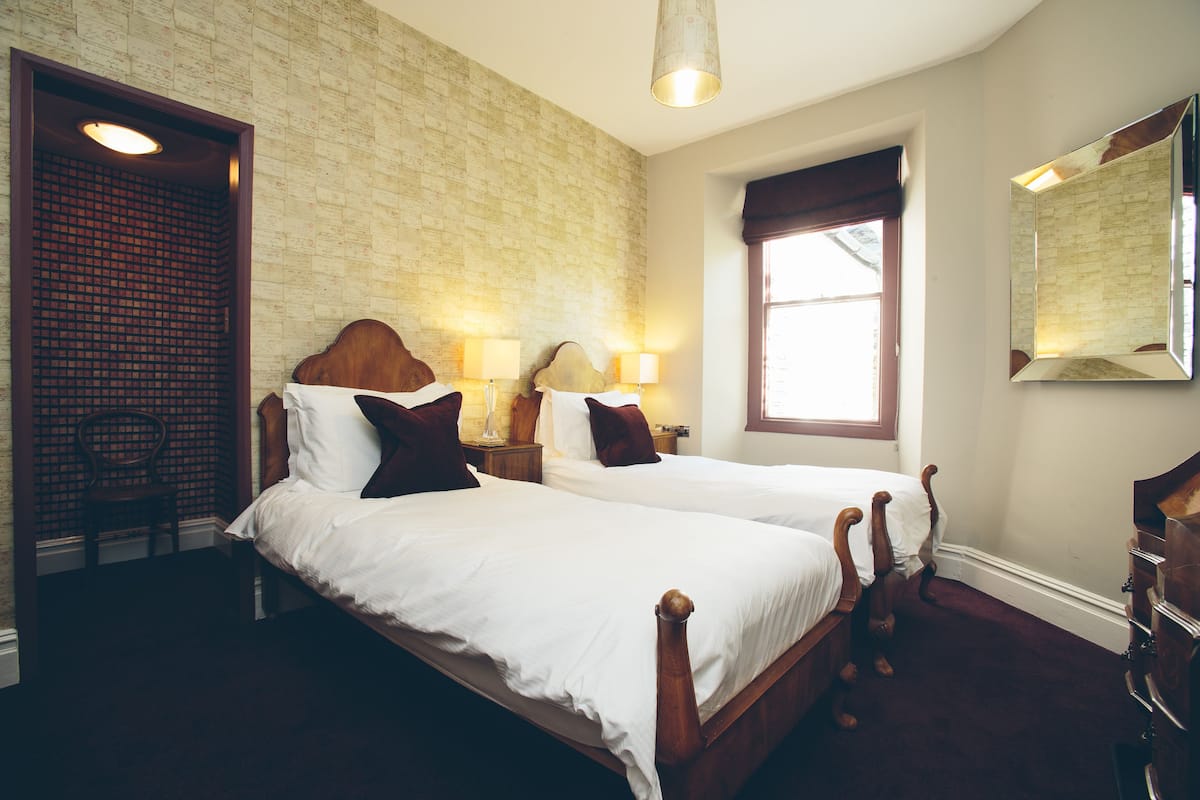 A room with two wooden beds, a chair, a dresser, and a large mirror.