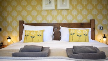 Una cama bien tendida con dos almohadas, cabecera de madera y una manta.