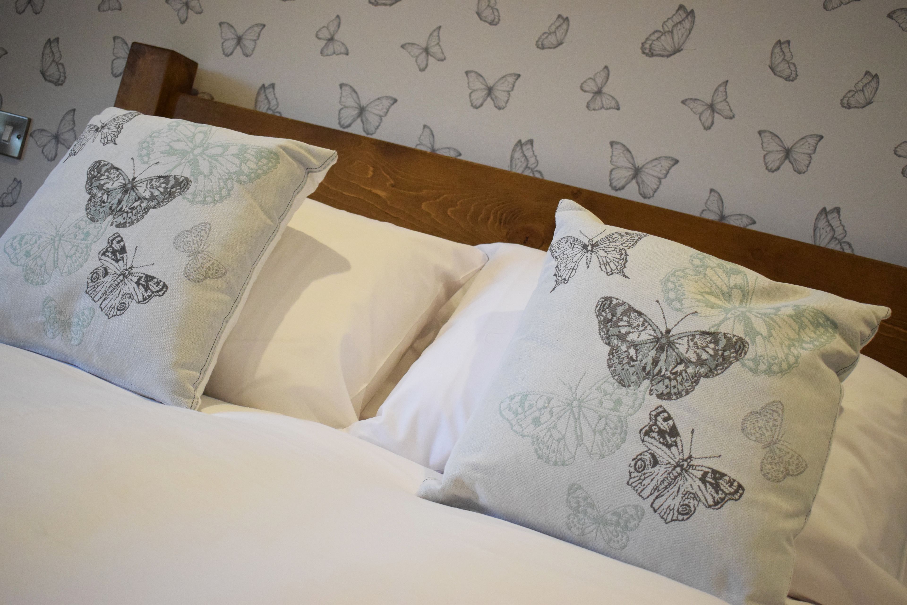Un letto con biancheria e cuscini decorati con motivi a farfalla.