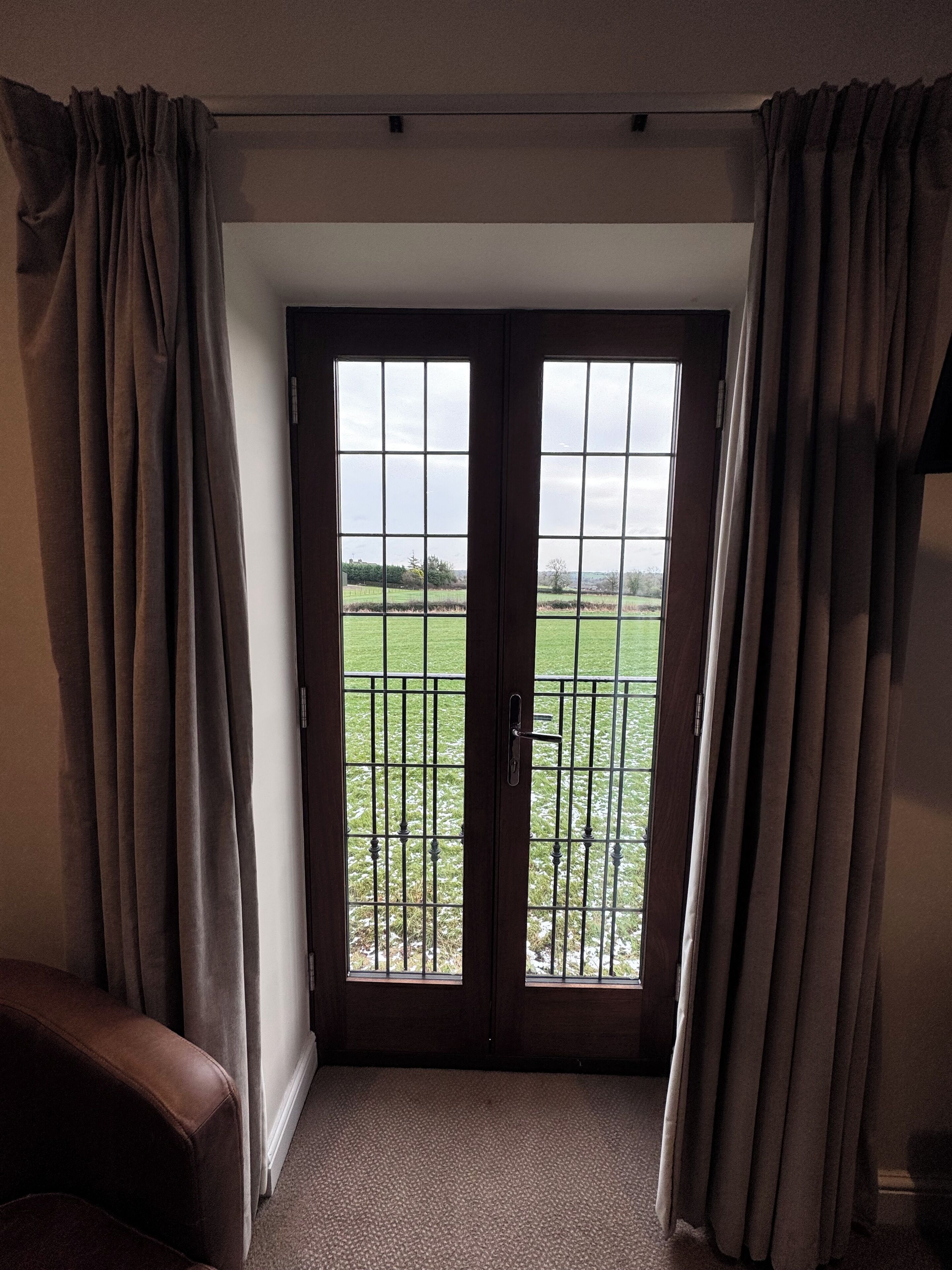Una habitación con una puerta que da a un balcón con barandilla de metal.