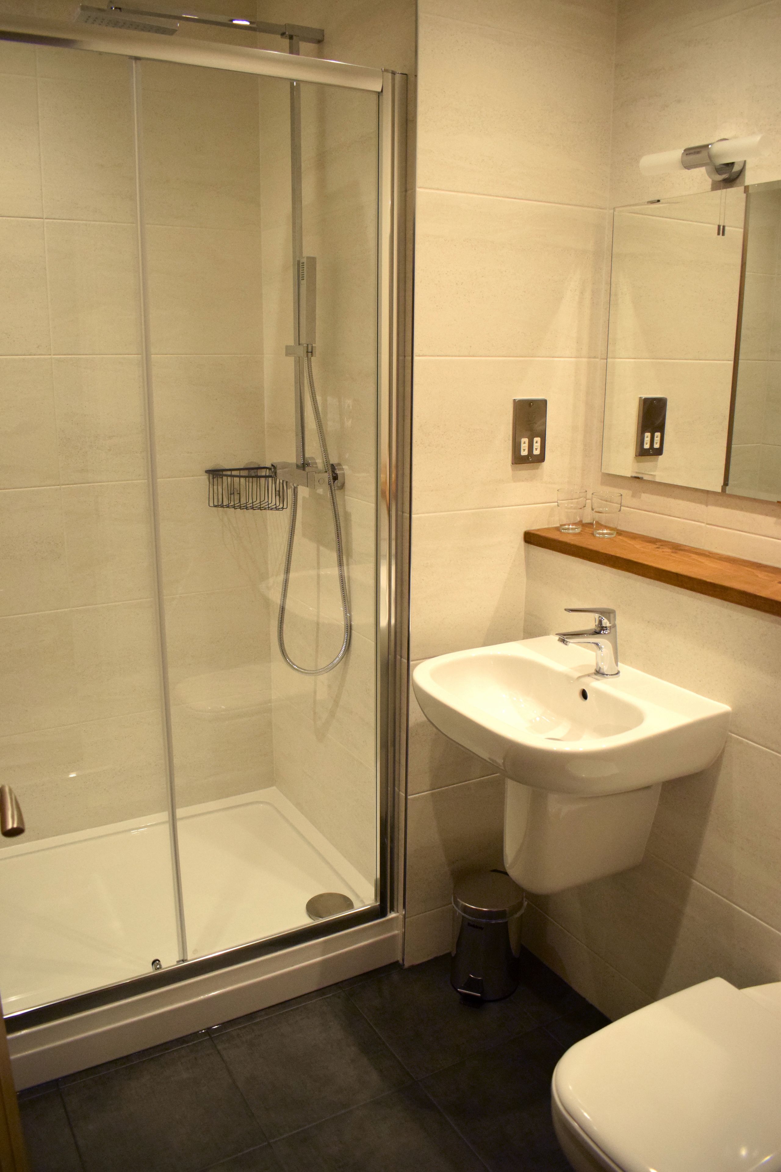 A bathroom with a glass-enclosed shower, a white sink, and a mirror above the sink.