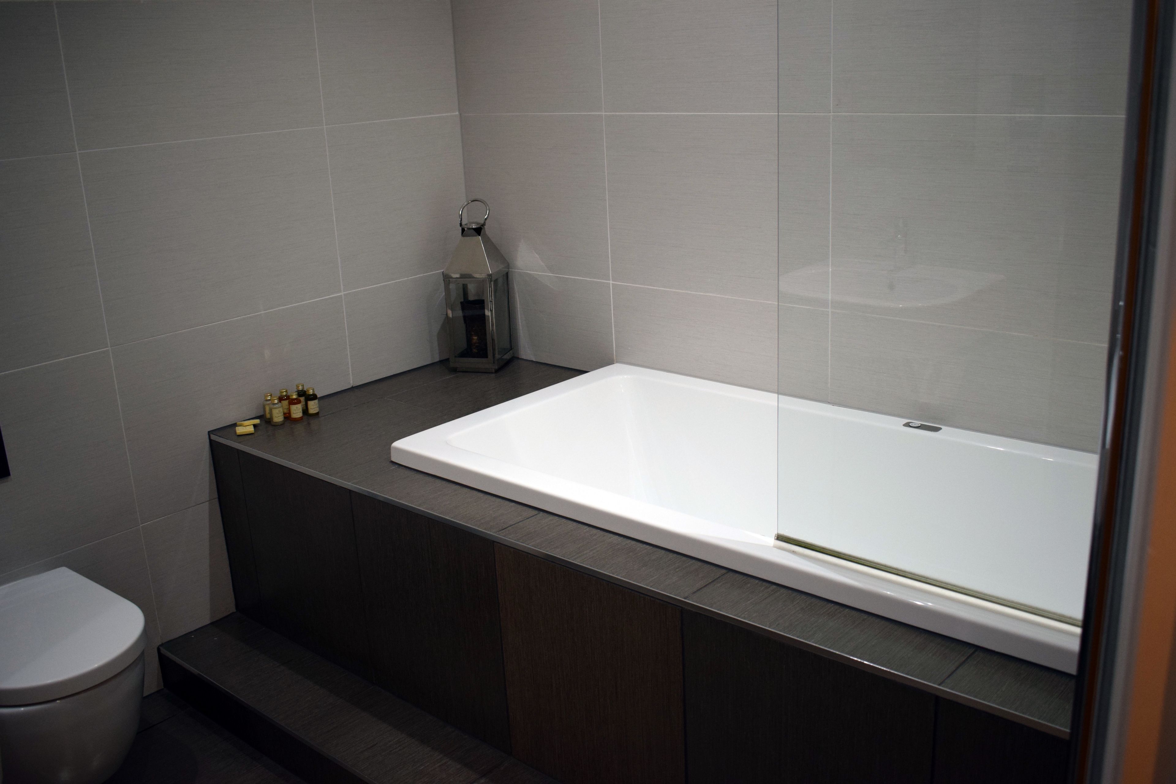 A modern bathroom with a large bathtub, dark wood cabinetry, and a small decorative lantern.