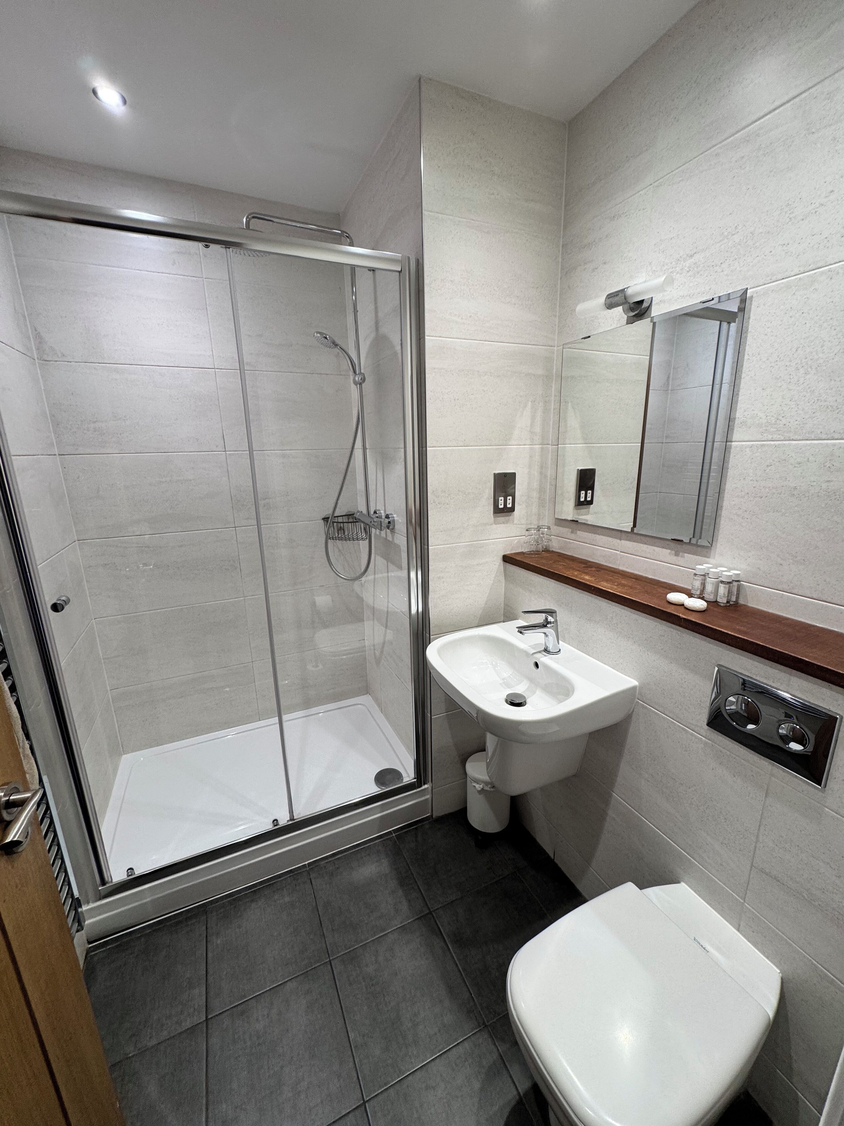 Une salle de bain moderne avec une douche à parois de verre, un lavabo blanc et des toilettes.