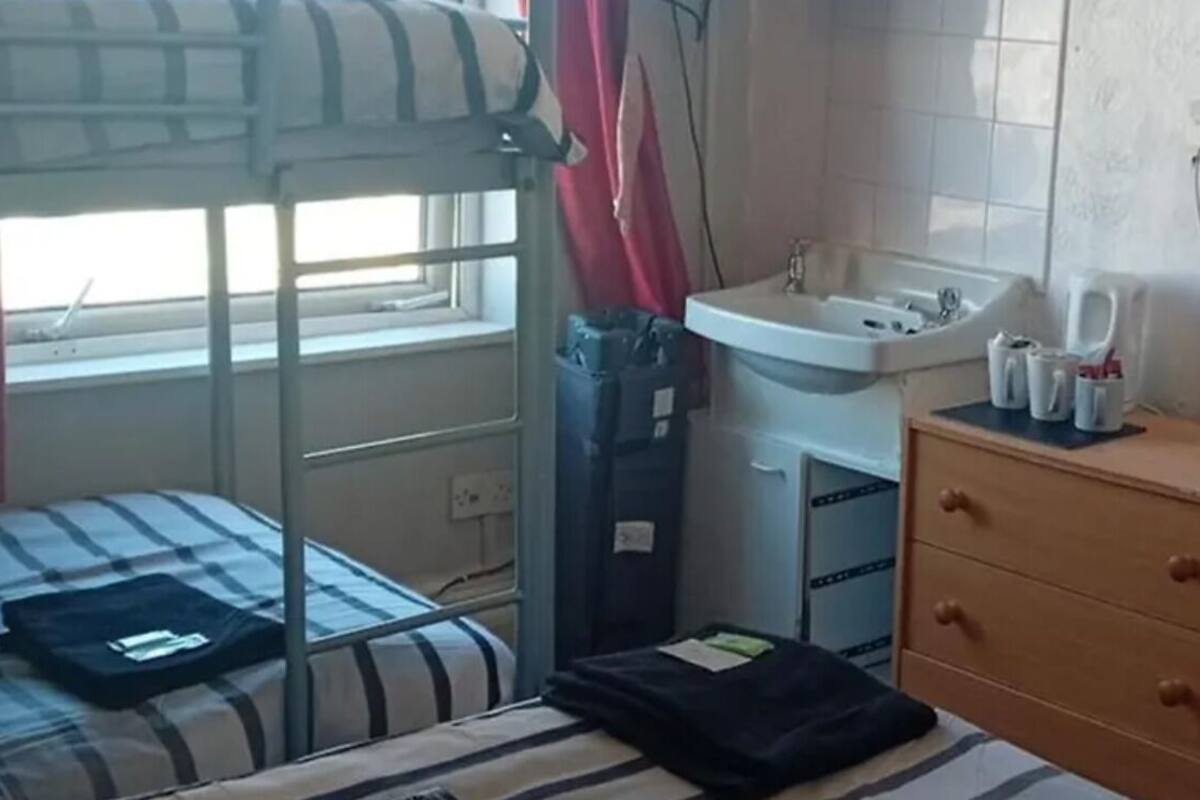 Una cama litera con ventana, un lavabo y un aparador de madera.