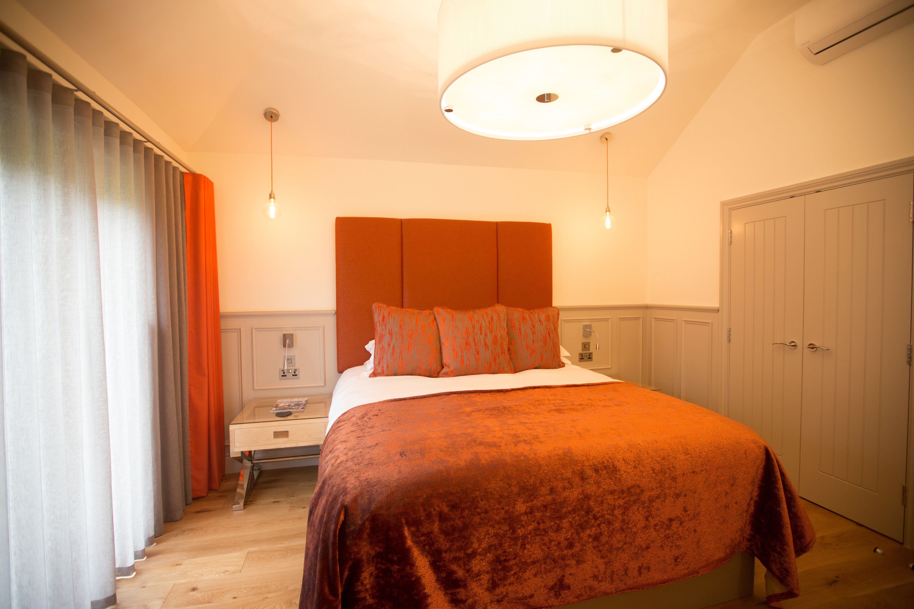 A bedroom with a large bed, a nightstand, a dresser, and a wardrobe.