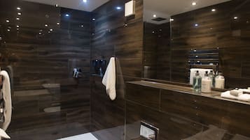 Une salle de bain moderne avec une douche à parois de verre, un lavabo blanc et un grand miroir.
