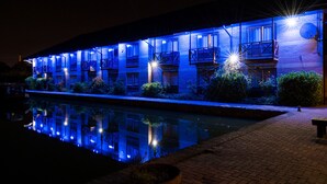 Un hotel con piscina, varios balcones y fachada de ladrillo por la noche.