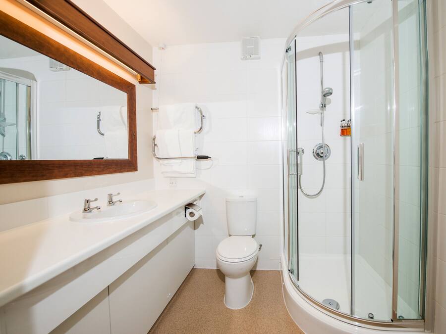 A modern bathroom with a glass-enclosed shower, a white sink, and a toilet.