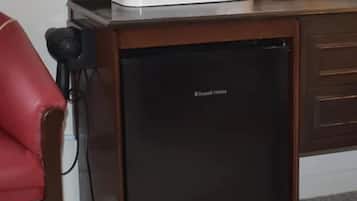 Un refrigerador compacto con una cafetera y un hervidor encima.